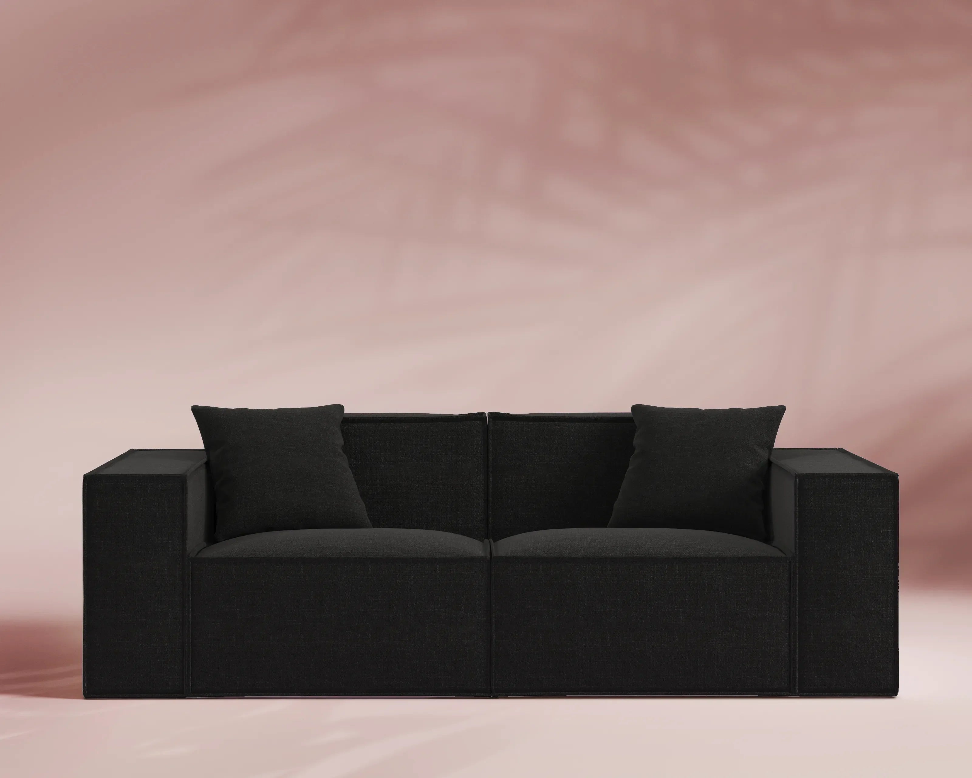 Black sofa with cushions on a pink background