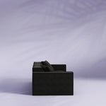 Black sofa against a light purple background